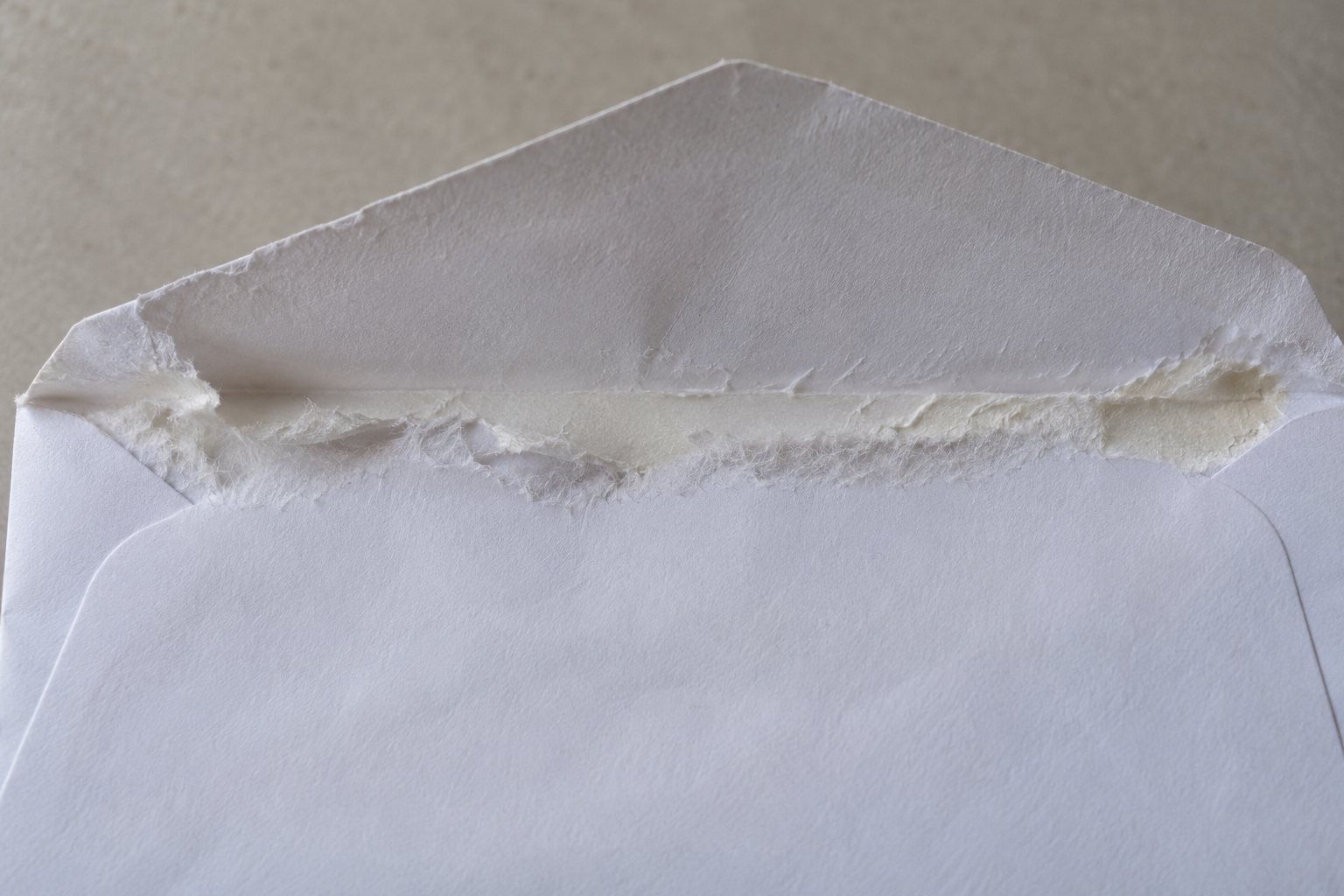 Torn paper fibers along an opened envelope flap